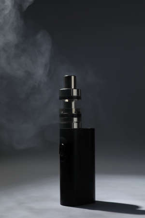 Electronic cigarette and smoke on dark gray background