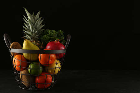 Fresh ripe fruits in metal basket on black table, space for textの写真素材