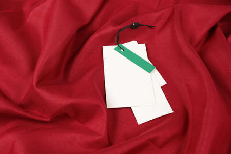 Blank white tags on red fabric. Space for textの写真素材
