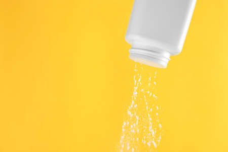 Scattering of dusting powder on orange background, space for textの写真素材