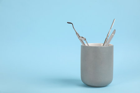 Holder with set of dentist's tools on light blue background. Space for textの写真素材