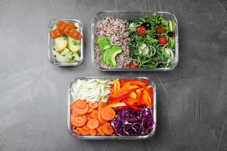 Set of glass containers with fresh food on gray table, flat lay