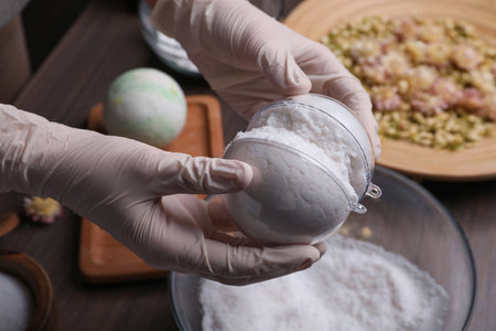 Woman in gloves making bath bomb at table, closeupの写真素材