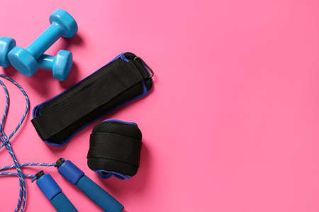 Blue weighting agents, dumbbells and skipping rope on pink background, flat lay. Space for textの写真素材