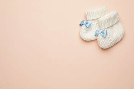 Knitted baby booties on light pink background, flat lay. space for textの写真素材