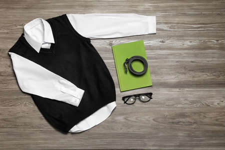 Stylish school uniform, glasses and notebook on wooden background, flat lay. Space for textの写真素材