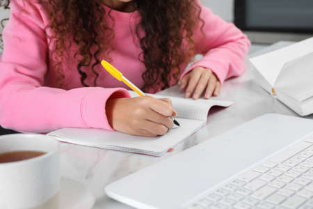 African American woman with modern laptop studying in kitchen, closeup. distance learning