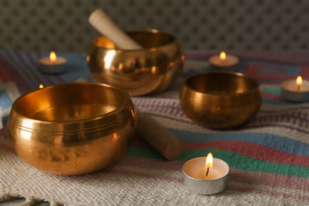 Tibetan singing bowls with mallets and burning candles on colorful fabricの写真素材
