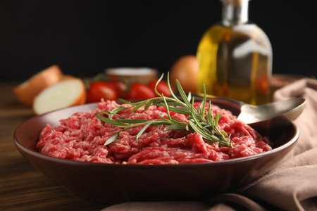 Fresh minced meat with rosemary on wooden table, closeupの写真素材