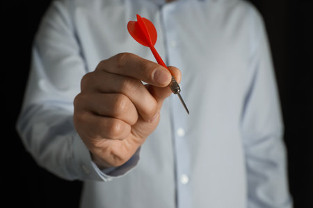 Man holding red dart on black background, closeupの写真素材
