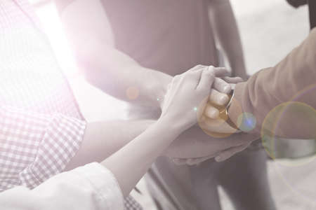Group of people holding hands together outdoors, closeup. black and white effect