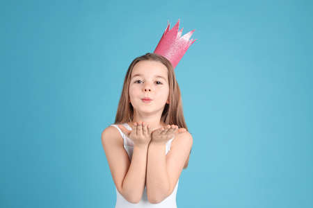 Cute girl in pink crown on light blue background. little princessの写真素材
