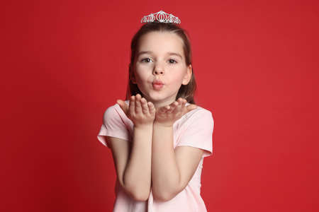 Cute girl in diadem on red background. little princessの写真素材