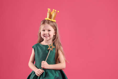Cute girl in fairy dress with golden crown and magic wand on pink background, space for text. little princessの写真素材