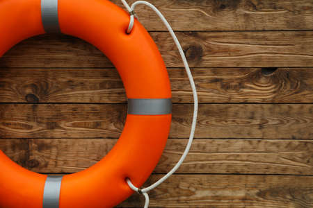 Orange lifebuoy on wooden background, space for text. Rescue equipmentの写真素材