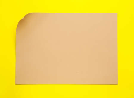 Sheet of brown paper on yellow background, top viewの写真素材