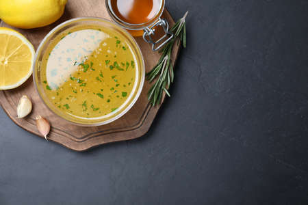 Bowl of lemon sauce and ingredients on dark table, top view with space for text. Delicious salad dressingの写真素材