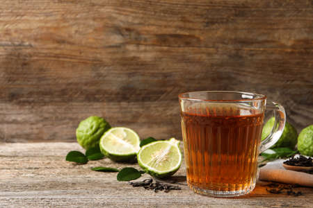 Glass cup of tasty bergamot tea and fresh fruits on wooden table, space for textの写真素材