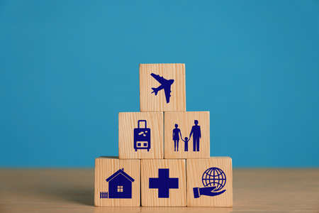 Cubes with different icons on wooden table against light blue background. insurance concept
