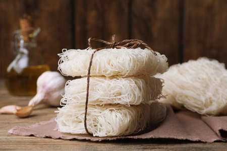 Stacked uncooked rice noodles on wooden table