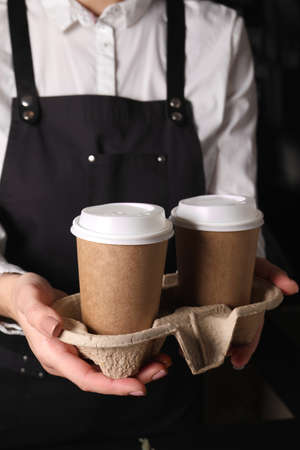 Barista holding takeaway paper cups with coffee in cafe, closeupの写真素材