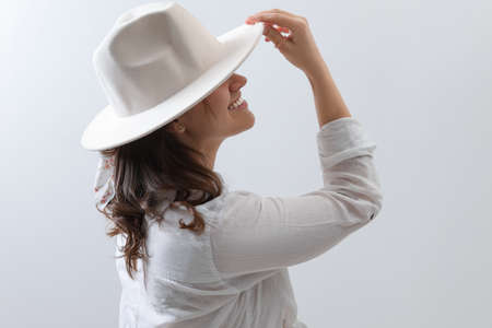 Happy young woman with hat and stylish bandana on light backgroundの写真素材