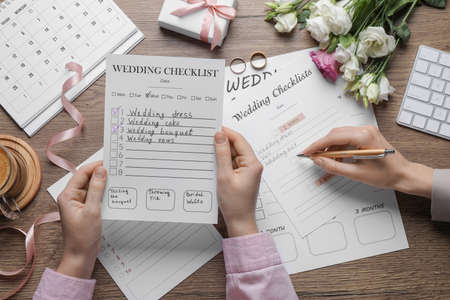 Women filling Wedding Checklists on wooden table, top viewの写真素材