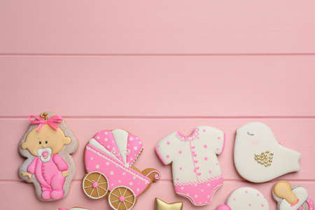 Cute tasty cookies of different shapes and space for text on pink wooden table, flat lay. baby shower partyの写真素材