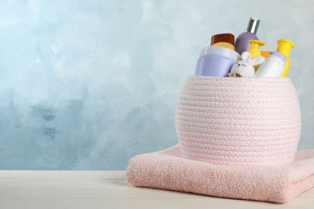 Basket with different baby cosmetic products, toy and towel on white wooden table. Space for textの写真素材