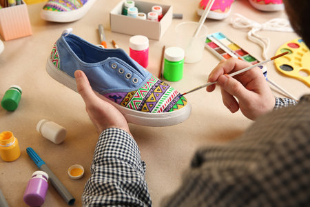 Man painting on sneaker at table, closeup. custom shoesの写真素材