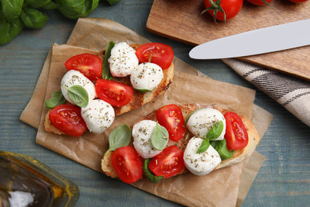 Delicious sandwiches with mozzarella, fresh tomatoes and basil on blue wooden table, flat layの写真素材