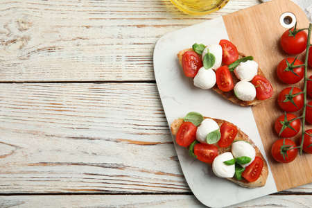 Delicious sandwiches with mozzarella, fresh tomatoes and basil on white wooden table, flat lay. Space for textの写真素材