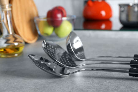 Set of different cooking utensils on gray countertop in kitchen, closeup
