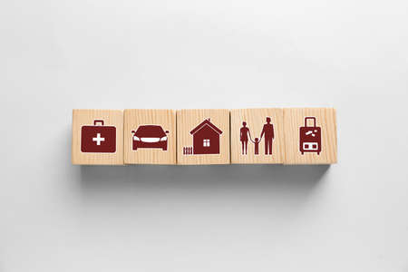 Wooden cubes with different icons on white background, flat lay. insurance concept