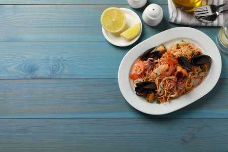 Delicious spaghetti with seafood served on turquoise wooden table, flat lay. Space for textの写真素材