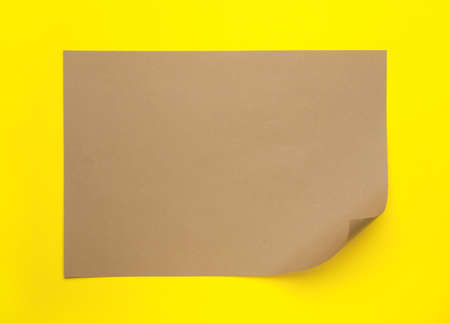 Sheet of brown paper on yellow background, top viewの写真素材