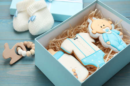 Set of baby shower cookies in gift box and accessories on turquoise wooden table, closeup
