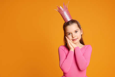 Cute girl in pink crown on yellow background, space for text. little princess