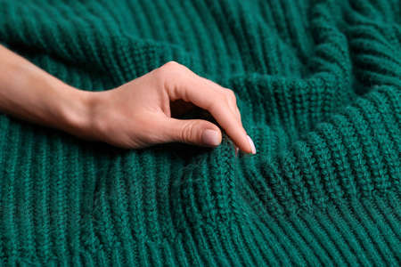 Woman touching soft green knitted textile, closeup