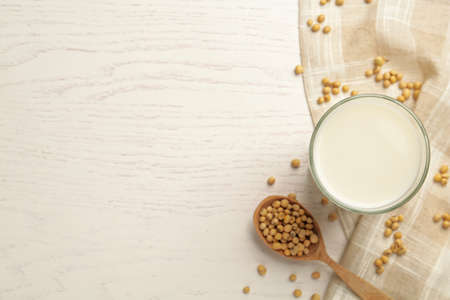 Glass with fresh soy milk and grains on white wooden table, flat lay. Space for textの写真素材