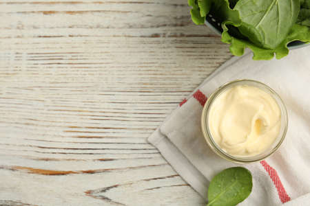 Jar of delicious mayonnaise and fresh spinach on white wooden table, flat lay. Space for textの写真素材