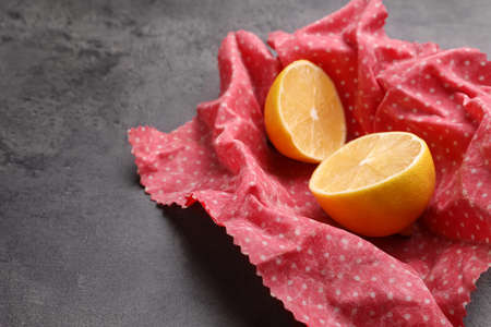 Halved lemon with beeswax food wrap on gray table, closeup. Space for textの写真素材