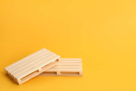 Wooden pallets on orange background, space for textの写真素材