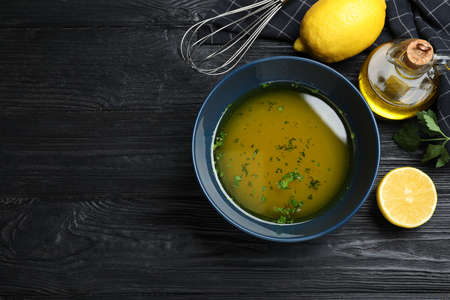 Bowl of lemon sauce and ingredients on black wooden table, flat lay with space for text. Delicious...
