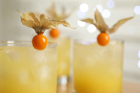 Refreshing cocktails decorated with physalis fruits against blurred festive lights, closeupの写真素材