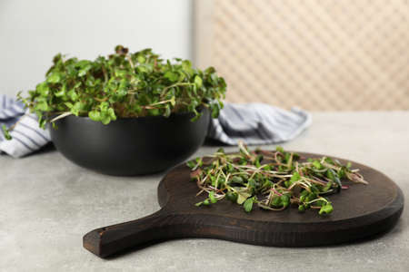Board and bowl with fresh radish microgreens on light gray tableの写真素材