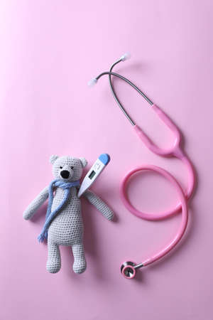 Toy bear with thermometer and stethoscope on pink background, flat layの写真素材