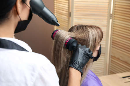 Professional stylist working with client in beauty salon, closeup. Hairdressing services during Coronavirus quarantineの写真素材