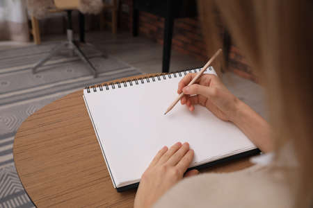 Woman drawing in sketchbook with pencil at home, closeupの写真素材