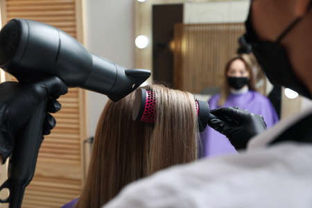 Professional stylist working with client in beauty salon, closeup. Hairdressing services during...
